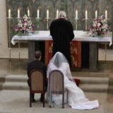 Das Brautpaar sitzend vorm Altar.