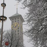 Detailansicht des Glockenturms der Pfarrkirche St. Josef in Straubing, umrahmt vom gefrorenen Raureif an den BÃ¤umen.