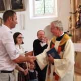 Pfarrer Franz Schmidbauer gratuliert den Eltern und dem Taufpaten.