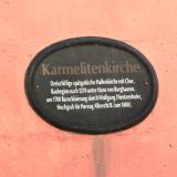 An der Fassade ist ein Schild angebracht mit folgendem Inhalt: "Karmelitenkirche: Dreischiffige spÃ¤tgotische Hallenkirche mit Chor, Baubeginn nach 1370 unter Hans von Burghausen, um 1700 Barockisierung durch Wolfgang Dientzenhofer, Hochgrab fÃ¼r Herzog Albrecht II. (um 1400).