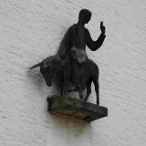 ... der künstlerisch gestalteten Figur des "Segnenden Christus, auf einem Esel reitend" an der Fassade befestigt.